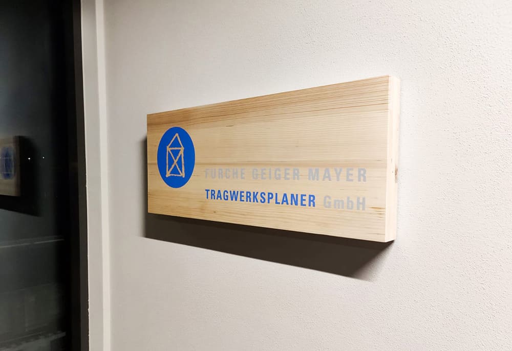 Holztafel an einer Eingangstür mit dem Logo der Furche Geiger Mayer Tragwerksplanung GmbH